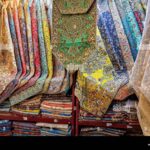 colorful-selection-of-termeh-traditional-persian-handwoven-cloth-embroidered-with-silk-displayed-in-a-handicraft-store-isfahan-iran-2X1JPD4